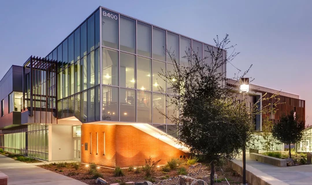 Irvine Valley College's glass-walled B400 building lit up at dusk
